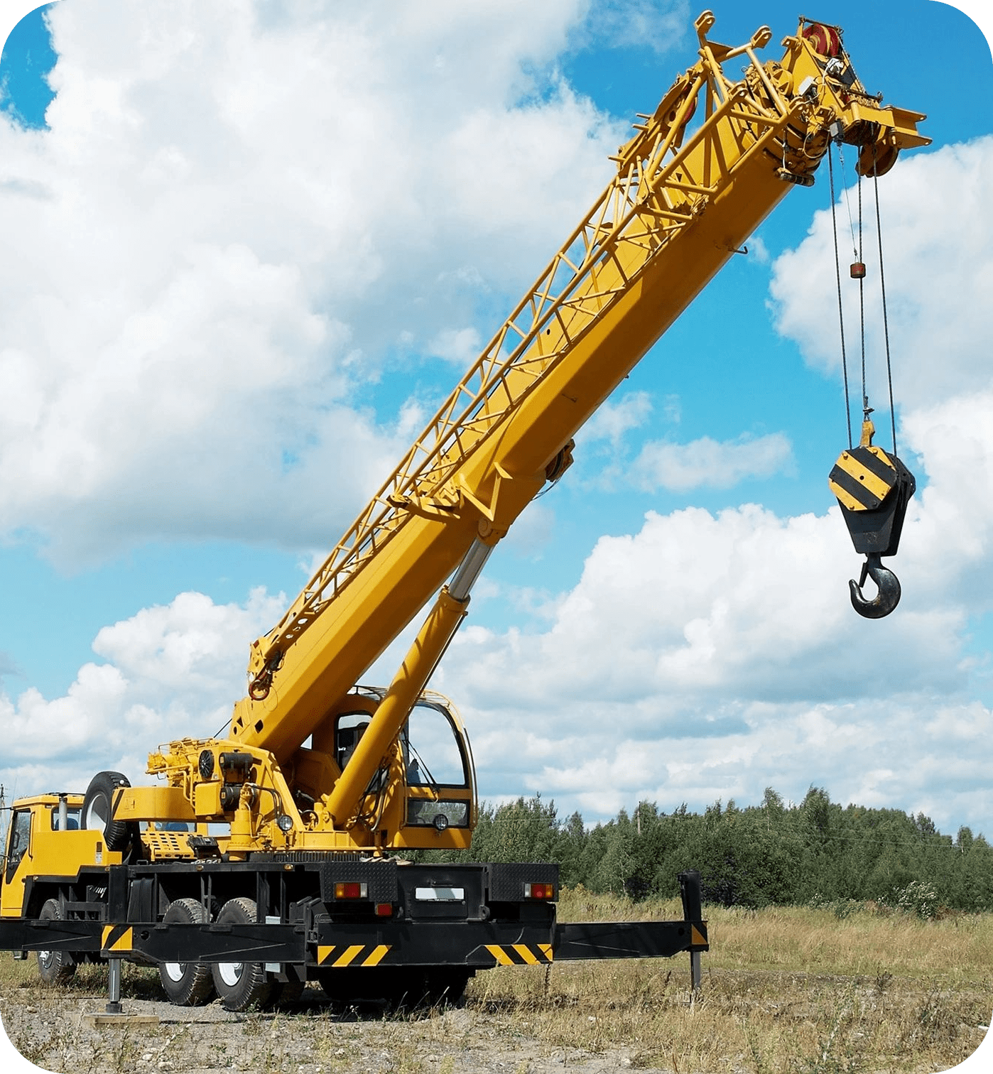 Yellow crane truck on grassy field.